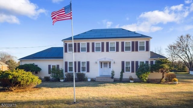 colonial inspired home with solar panels and a front lawn