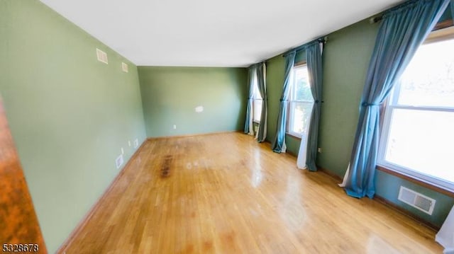 empty room with light hardwood / wood-style floors and a wealth of natural light