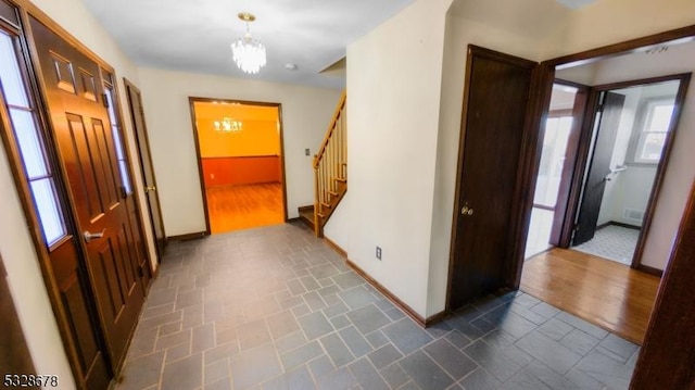 hall with dark hardwood / wood-style floors, a wealth of natural light, and a notable chandelier