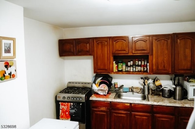 kitchen featuring stainless steel gas stove, a sink, and dark brown cabinets