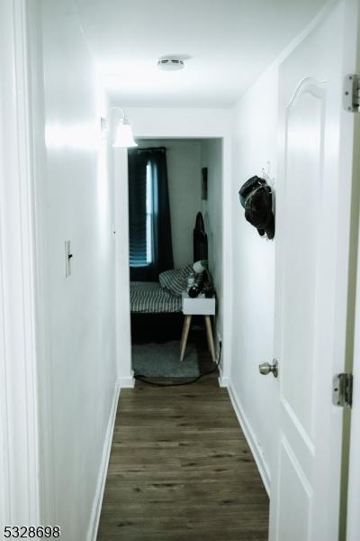 hall with baseboards and dark wood-type flooring