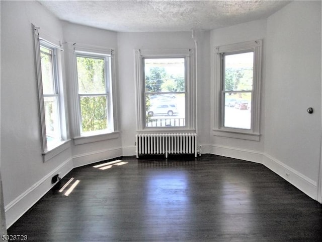 spare room featuring a textured ceiling, dark hardwood / wood-style floors, and radiator