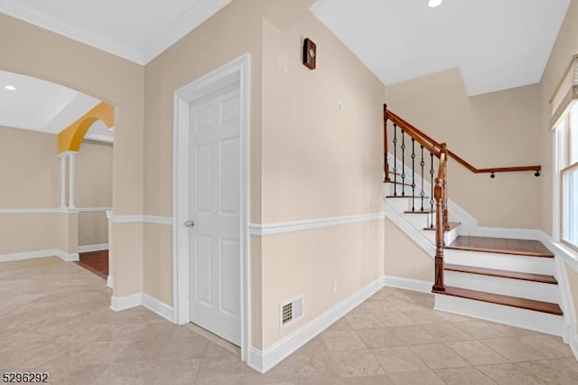 stairway with tile patterned floors and ornamental molding