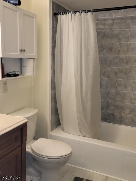 full bathroom with shower / bath combo, vanity, and toilet