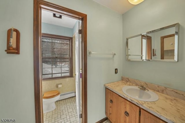 bathroom with tile patterned flooring, vanity, toilet, and a baseboard heating unit