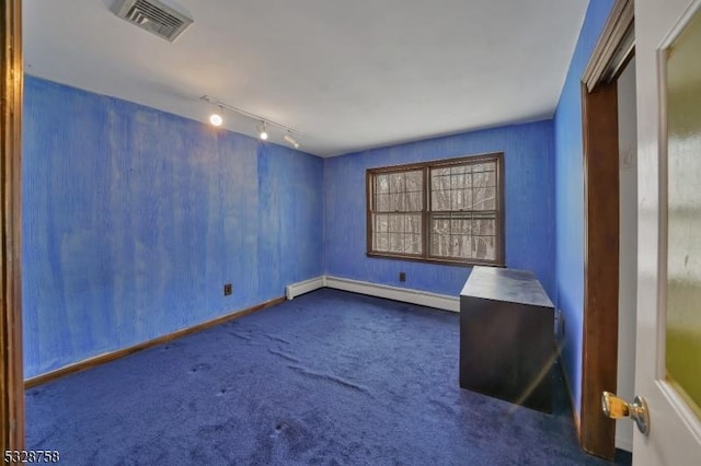 empty room with rail lighting, a baseboard radiator, and dark colored carpet