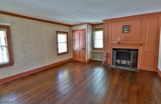 unfurnished living room featuring plenty of natural light, dark hardwood / wood-style flooring, crown molding, and radiator