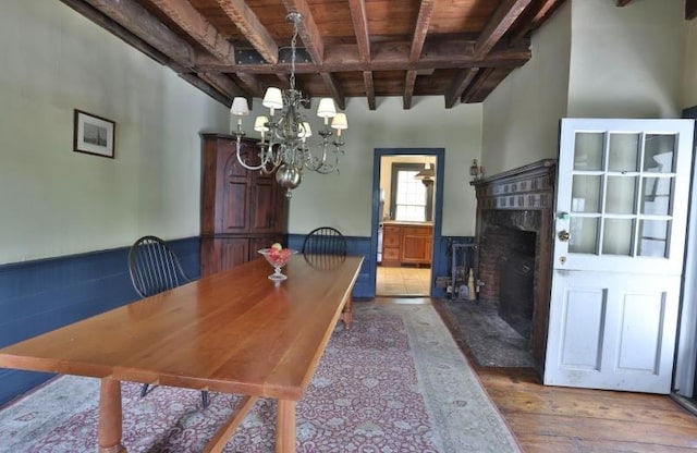 dining area featuring a high end fireplace, an inviting chandelier, hardwood / wood-style flooring, beamed ceiling, and wood ceiling