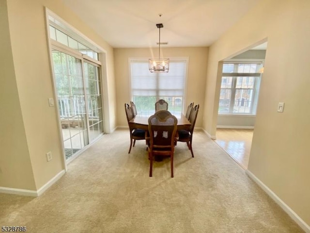 carpeted dining space with an inviting chandelier