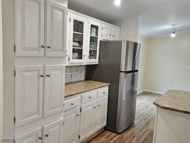 kitchen with stainless steel refrigerator, crown molding, white cabinets, and light stone countertops