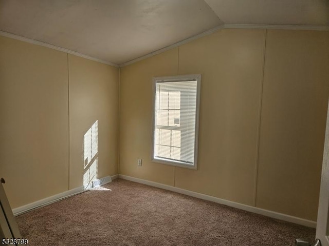 carpeted empty room featuring crown molding and vaulted ceiling