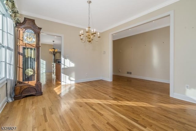 unfurnished dining area with wood-type flooring, ornamental molding, and a notable chandelier