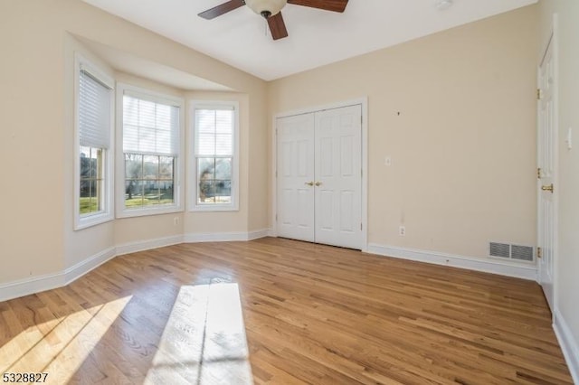 unfurnished bedroom with ceiling fan, light wood-type flooring, and a closet