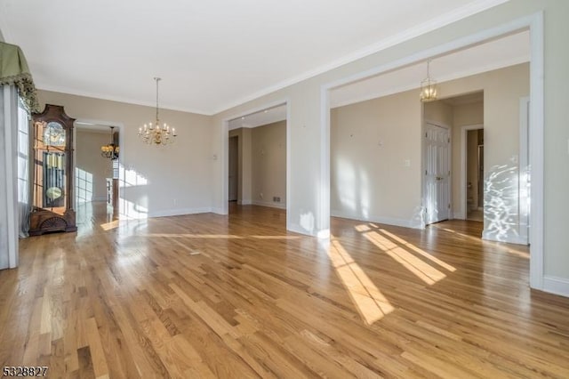 empty room featuring crown molding, a notable chandelier, and light wood-type flooring