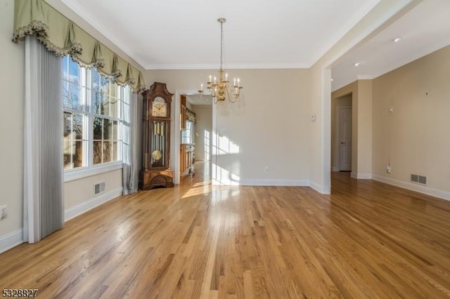 unfurnished dining area with light hardwood / wood-style floors, an inviting chandelier, and ornamental molding