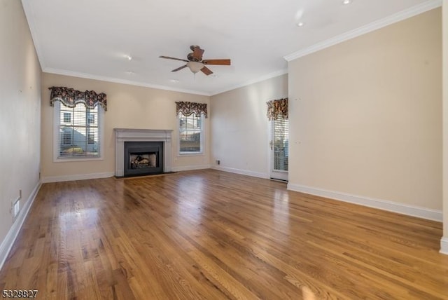 unfurnished living room with ceiling fan, ornamental molding, a wealth of natural light, and light hardwood / wood-style flooring