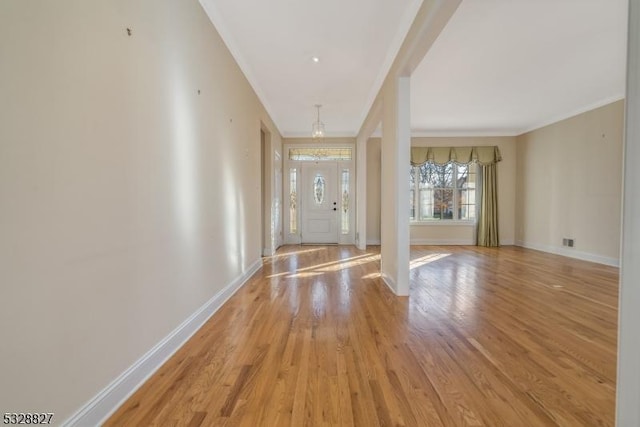 foyer entrance with crown molding, light hardwood / wood-style floors, and an inviting chandelier