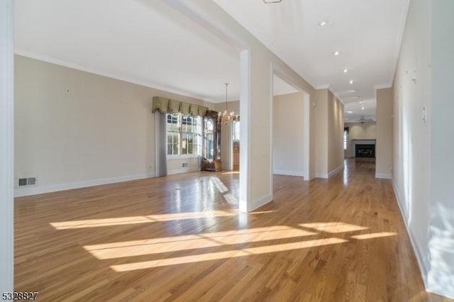 interior space with light hardwood / wood-style floors, crown molding, and an inviting chandelier