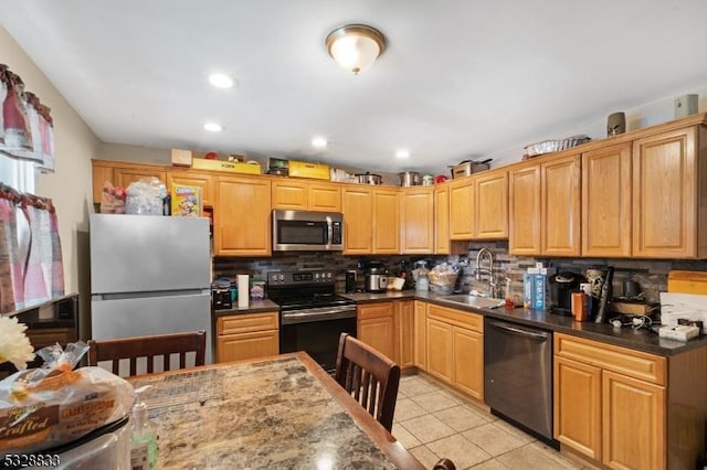 kitchen with backsplash, sink, dark stone countertops, light tile patterned floors, and appliances with stainless steel finishes