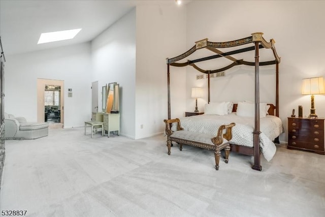 bedroom with high vaulted ceiling, light colored carpet, and a skylight