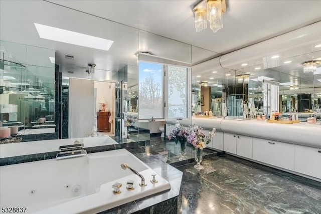 bathroom featuring tiled tub, vanity, and a skylight