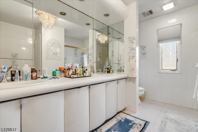 bathroom featuring toilet, vanity, tile walls, an inviting chandelier, and an enclosed shower