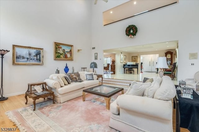 living room with light hardwood / wood-style floors and a towering ceiling