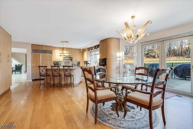 dining space featuring light wood-type flooring and an inviting chandelier