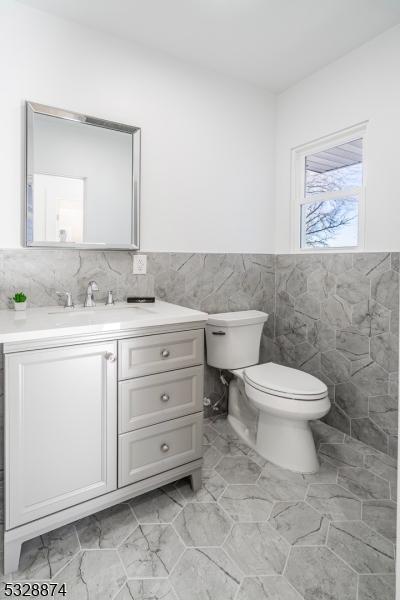 bathroom featuring vanity, toilet, and tile walls