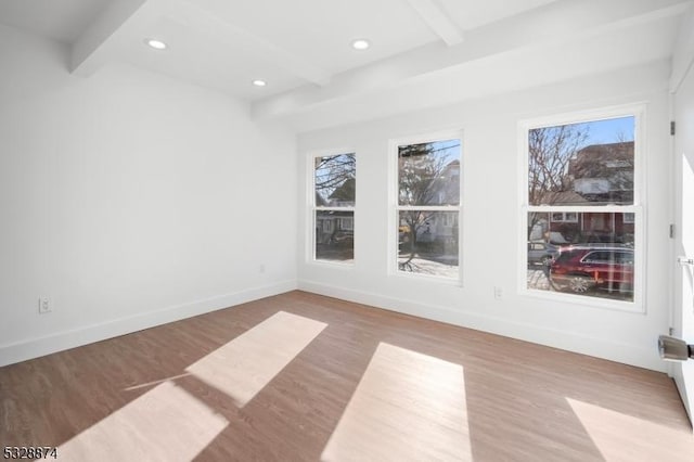 unfurnished room with beamed ceiling, a healthy amount of sunlight, and light wood-type flooring