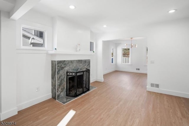 unfurnished living room with wood-type flooring, a fireplace, and an inviting chandelier