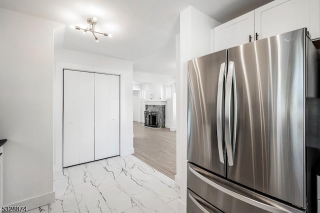 kitchen with stainless steel fridge, white cabinets, and a premium fireplace