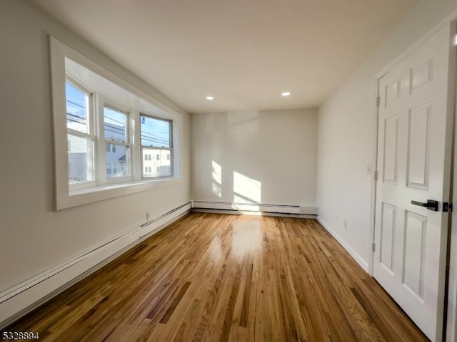 unfurnished room featuring wood-type flooring and a baseboard radiator