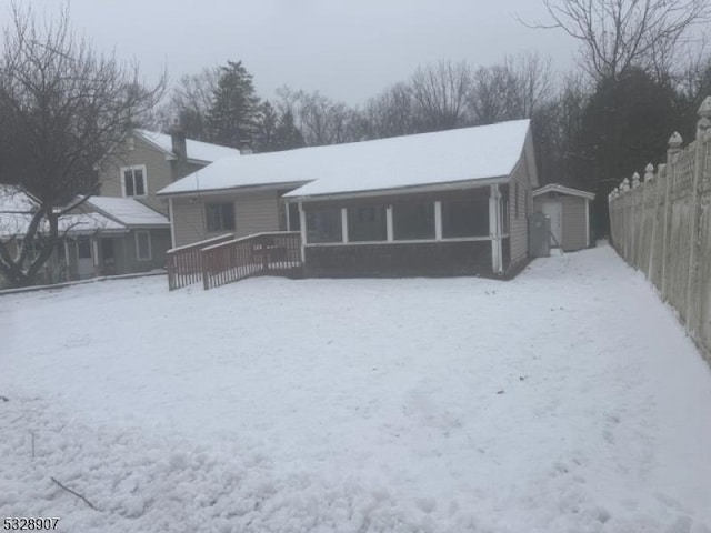 snow covered rear of property featuring a garage and an outdoor structure