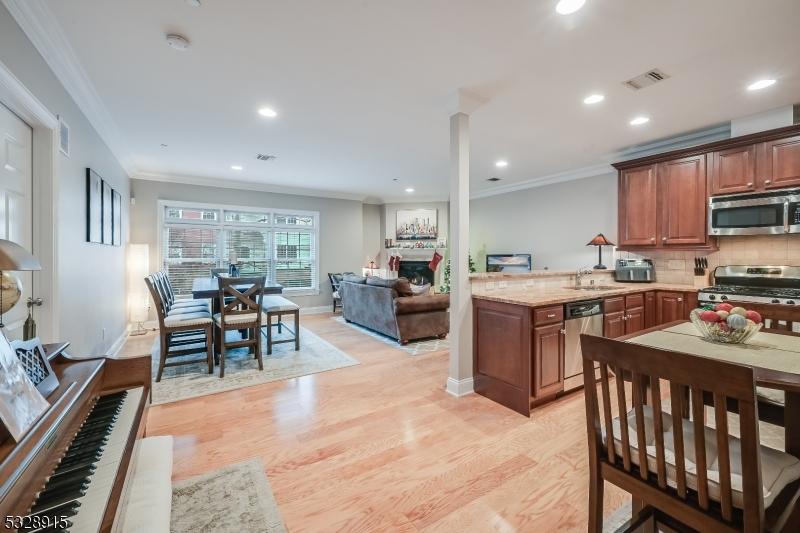 kitchen with ornamental molding, appliances with stainless steel finishes, light hardwood / wood-style flooring, and kitchen peninsula