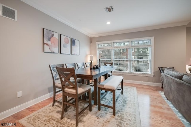 dining area with ornamental molding and light hardwood / wood-style floors