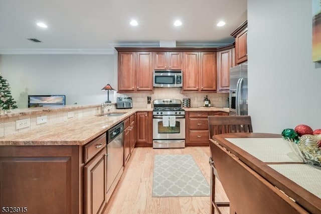 kitchen with sink, light wood-type flooring, ornamental molding, appliances with stainless steel finishes, and decorative backsplash