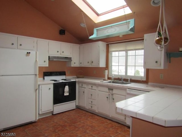 kitchen featuring white appliances, lofted ceiling with skylight, sink, tile countertops, and white cabinets