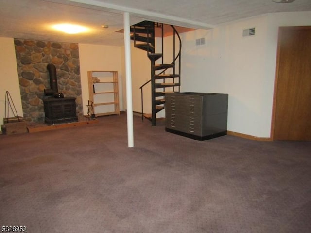 basement with dark carpet, a textured ceiling, and a wood stove