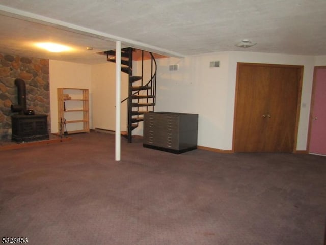 basement with dark carpet and a wood stove