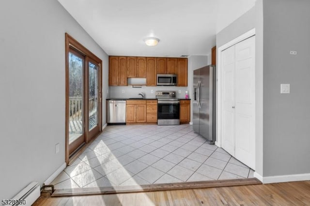 kitchen featuring french doors, a baseboard heating unit, sink, light tile patterned floors, and appliances with stainless steel finishes