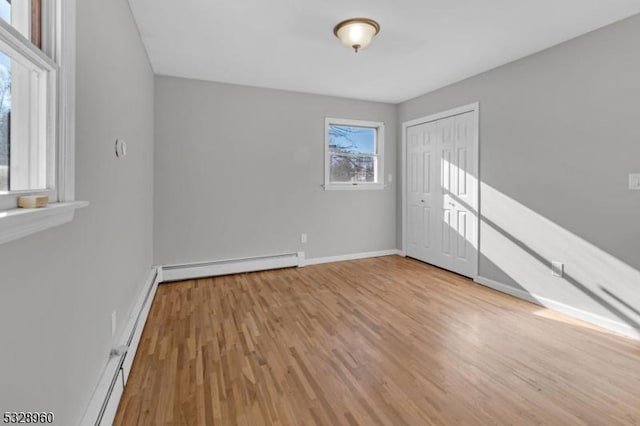 unfurnished room featuring a baseboard radiator and light hardwood / wood-style floors