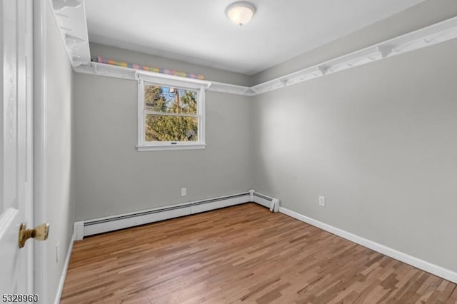 spare room featuring wood-type flooring and a baseboard radiator