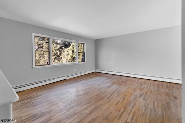 unfurnished room featuring wood-type flooring and a baseboard heating unit