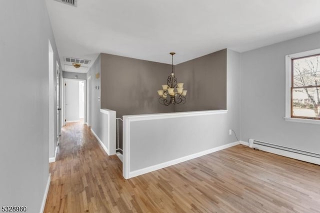 interior space with baseboard heating, light hardwood / wood-style floors, and an inviting chandelier