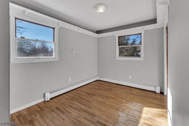 empty room with wood-type flooring and a baseboard heating unit