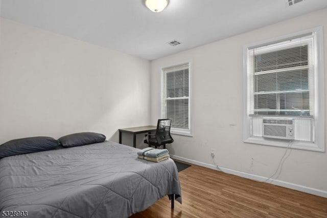 bedroom with cooling unit and wood-type flooring