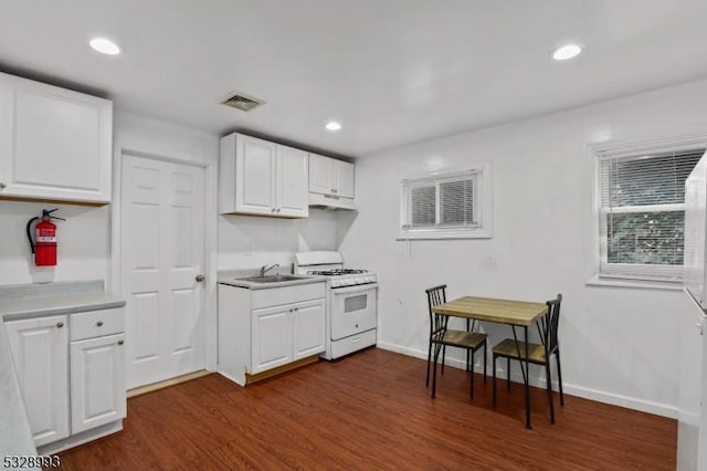 kitchen with dark wood-type flooring, white cabinetry, white gas stove, and sink