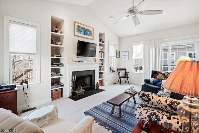 living room featuring carpet flooring, built in shelves, vaulted ceiling, and ceiling fan