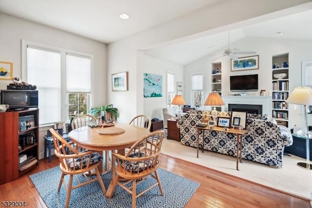 dining area with hardwood / wood-style floors, ceiling fan, built in shelves, and vaulted ceiling